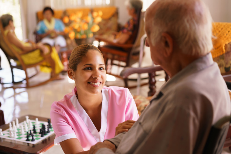 Nurse kneeling in front of a resident smiling. 