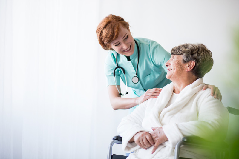 Nurse smiling at a resident with her hand on their shoulder. 