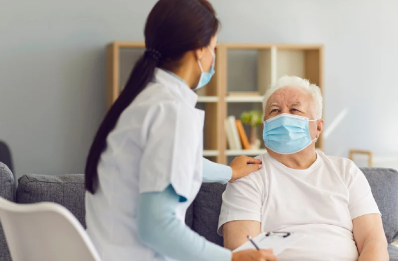 Nurse with her hand on the shoulder of a patient wearing a mask. 