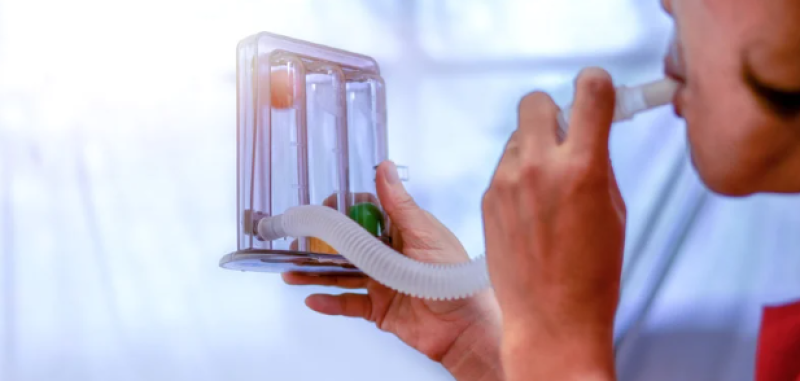 Woman using a device to test her lung strength. 
